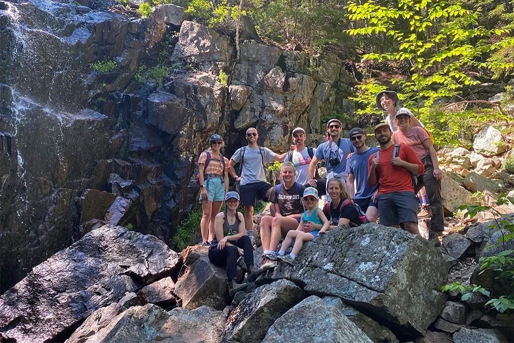 A group of U N E students standing on rocks during a hiking trip
