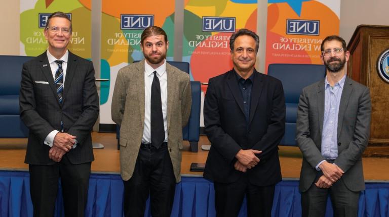 President Herbert and Anouar Majid stand with two speakers in front of banners for the U N E President's Forum